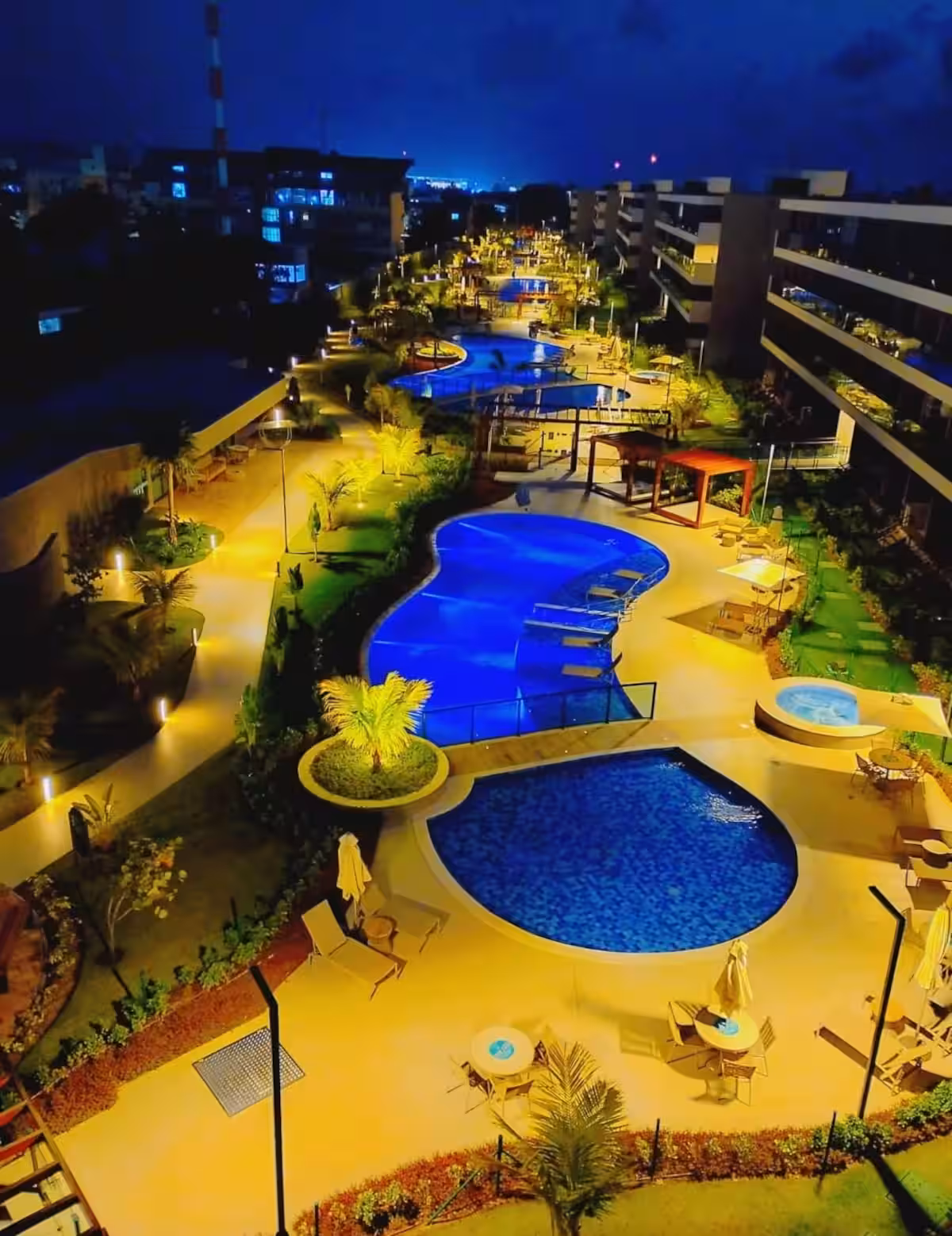 Condomínio iluminado à noite junto às piscinas
